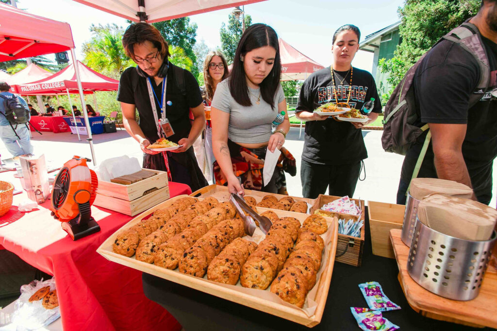 Tray of cookies on a table under a canopy with attendees selecting snacks during the event.