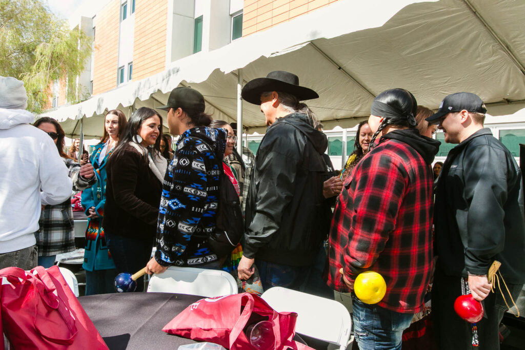 Attendees shake hands with performance group near the event tent.