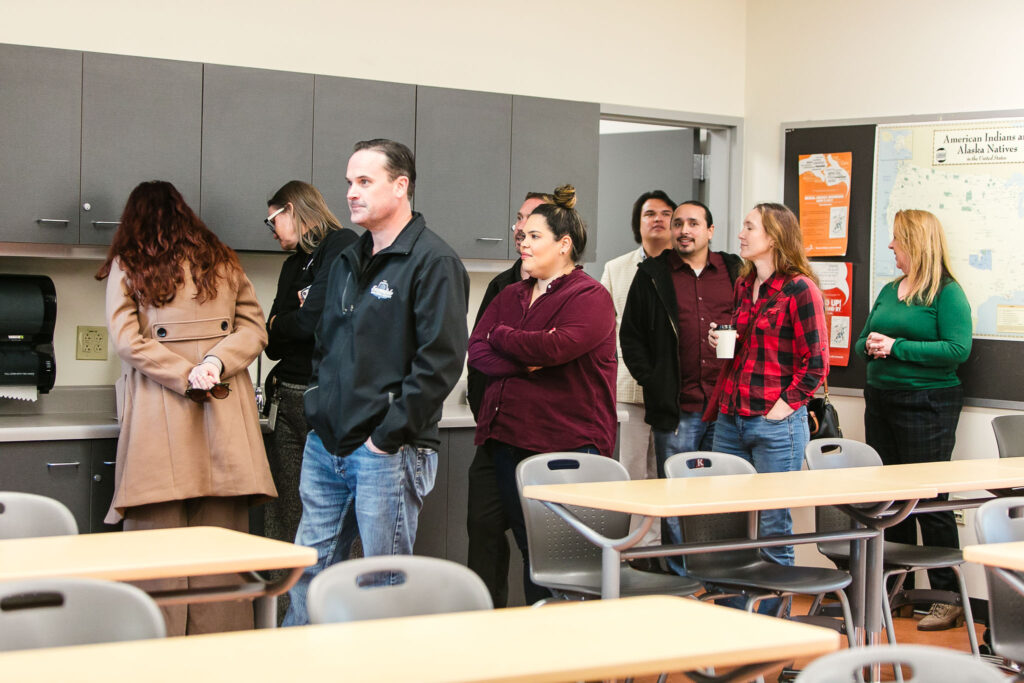 Several people standing in the American Indian Studies classroom.