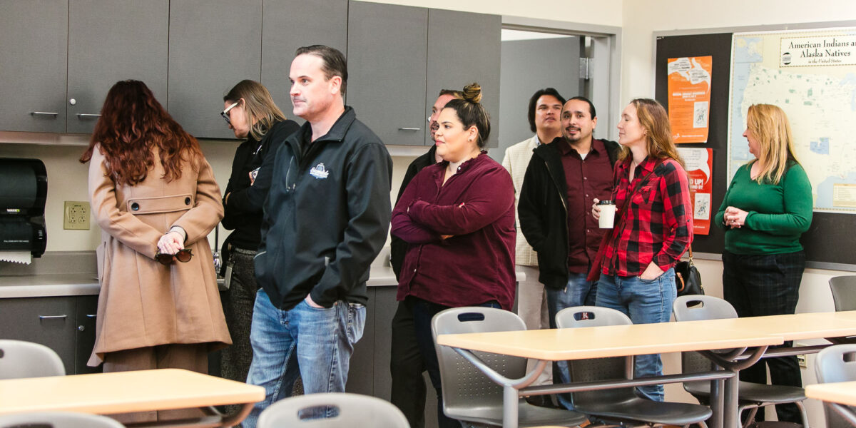 Several people standing in the American Indian Studies classroom.
