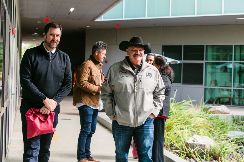 Two people walking and talking on a sidewalk with plants and rocks lining the pathway.