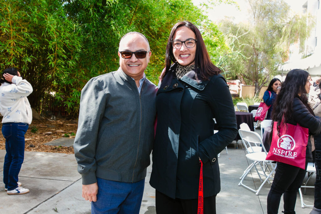 Two people standing together outdoors near the walkway and event tent.