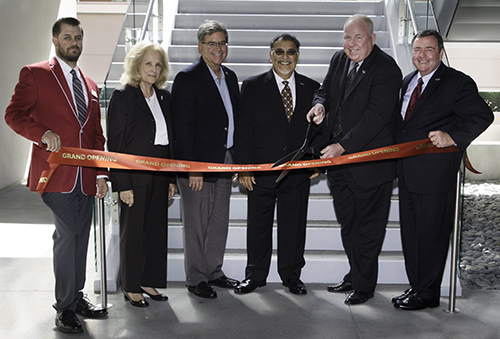 Governing board members standing behind a grand opening ribbon for the Humanities building