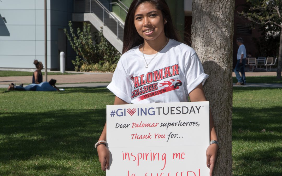 Student holding a Giving Tuesday sign that reads 'Dear Palomar superheroes, thank you for... inspiring me to to succeed!