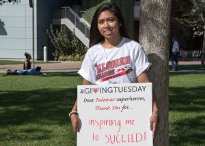Student holding a Giving Tuesday sign that reads 'Dear Palomar superheroes, thank you for... inspiring me to to succeed!