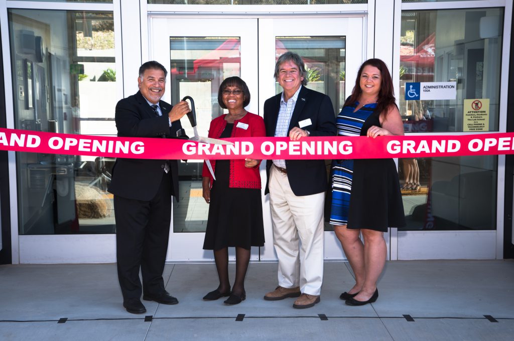 Palomar staff and leadership standing behind a red grand opening ribbon