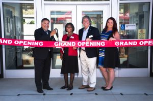 Palomar staff and leadership standing behind a red grand opening ribbon