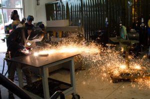 Students working with tools and creating sparks in welding class