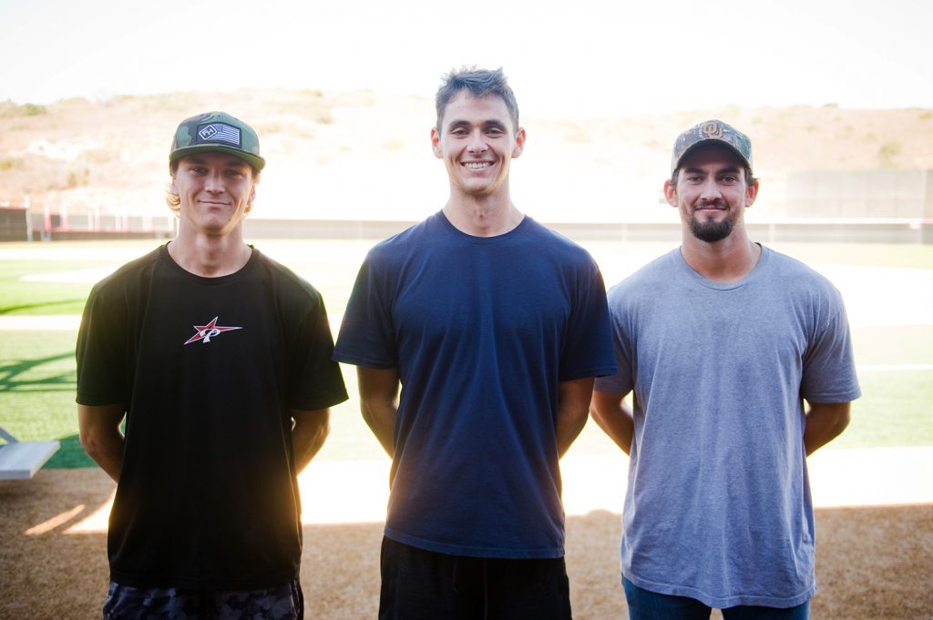 Three Comet baseball players standing on field
