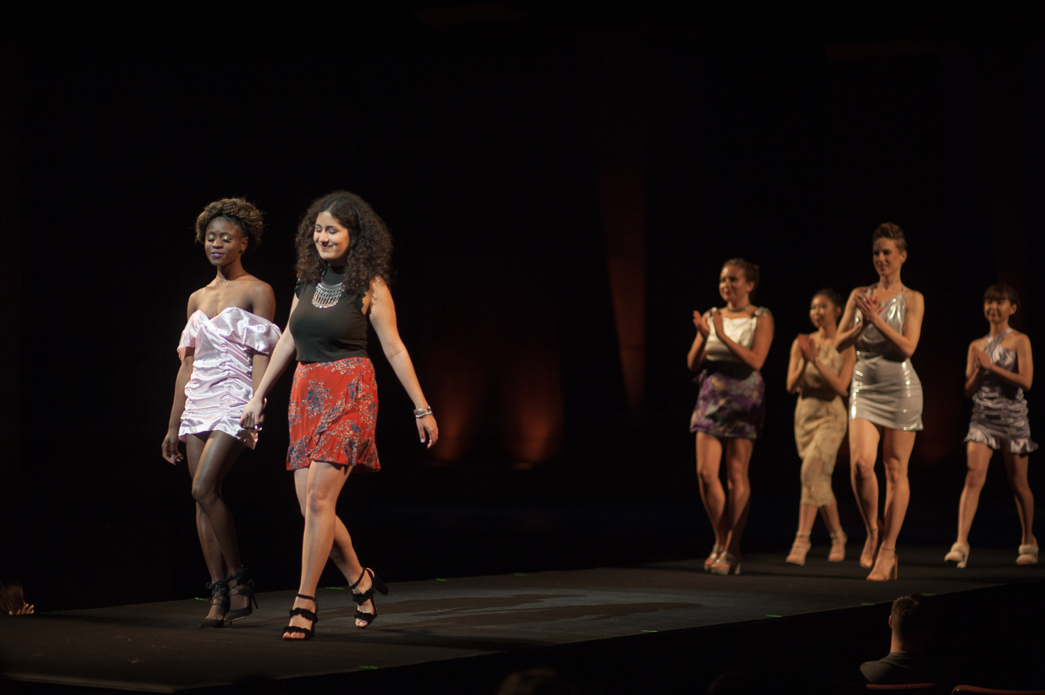 Designer walking on runway with models behind her clapping