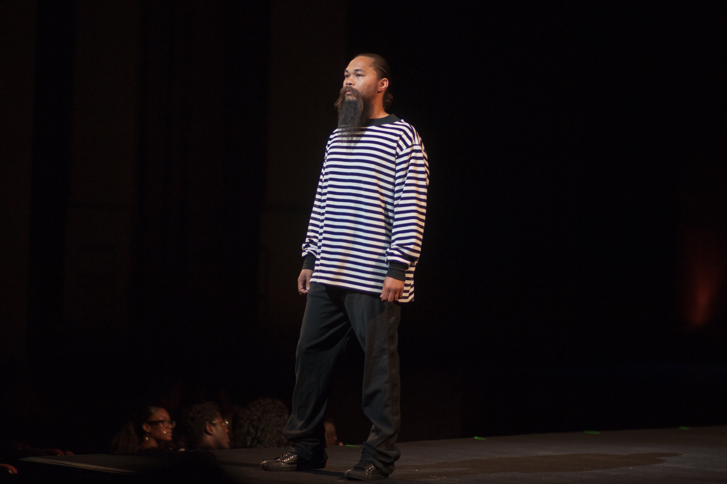 Male model posing on runway in black/white striped shirt