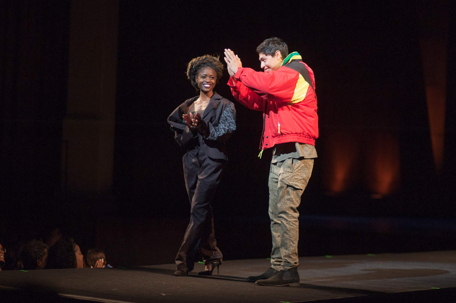 Student designer takes a bow on stage with one of the models at a fashion show