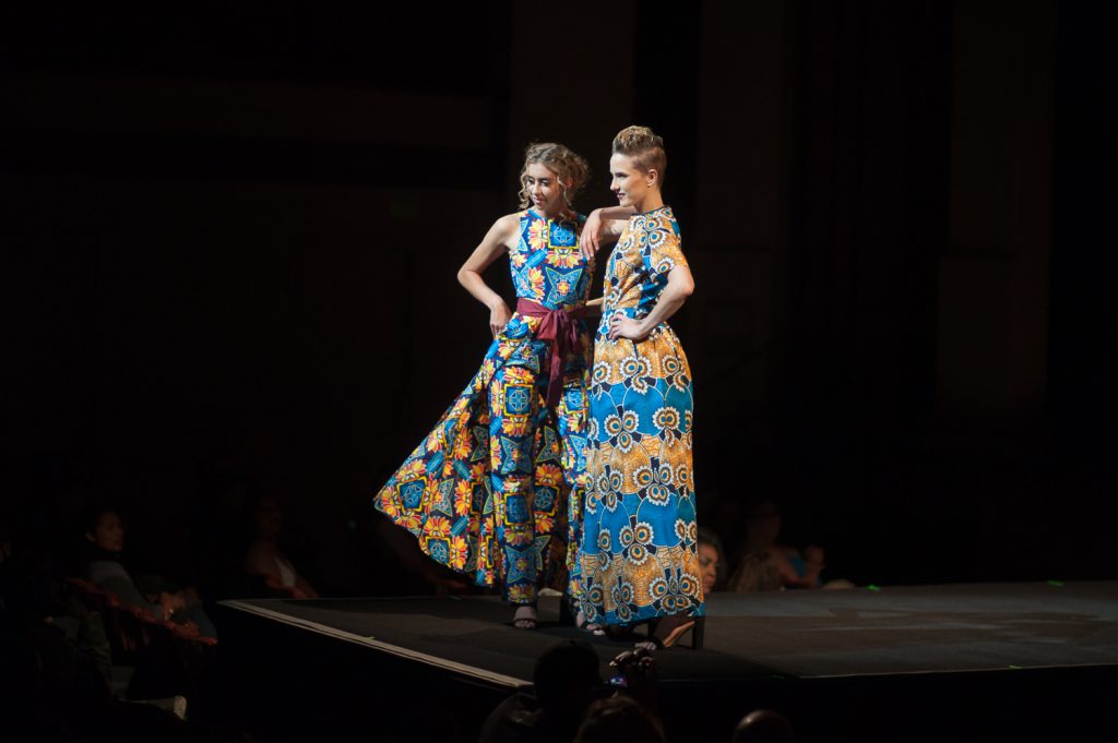 Two models posing on runway in bright patterned outfits