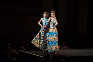 Two models posing on runway in bright patterned outfits