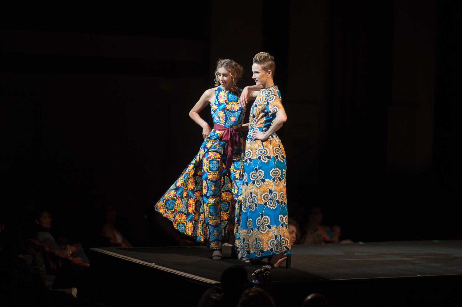 Two models posing on runway in bright patterned outfits