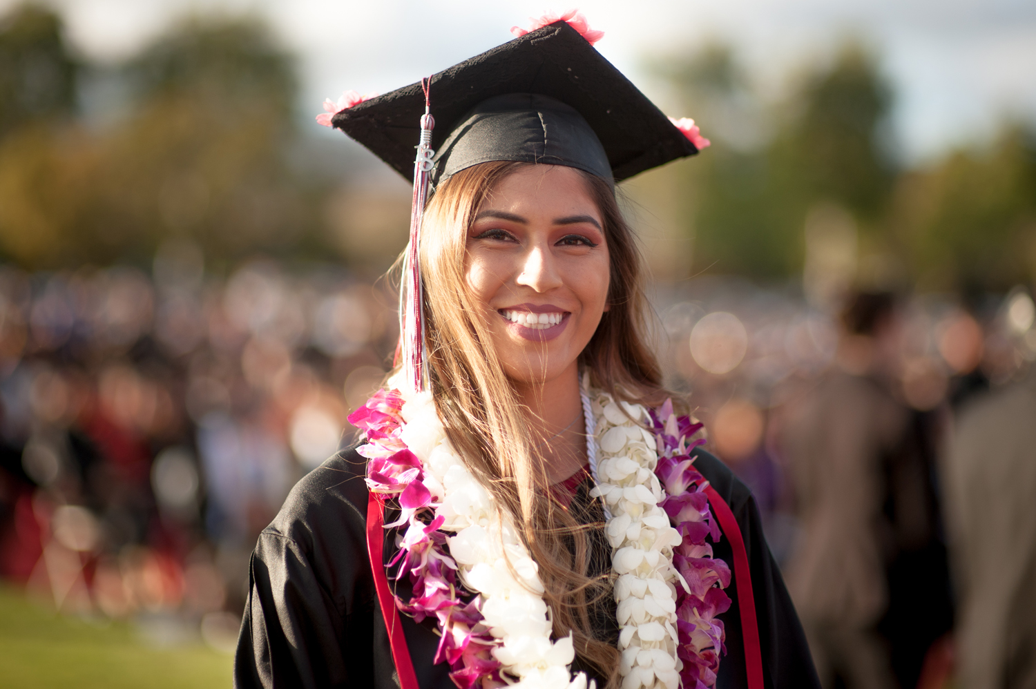 Graduate in cap and gown and wearing floral leis