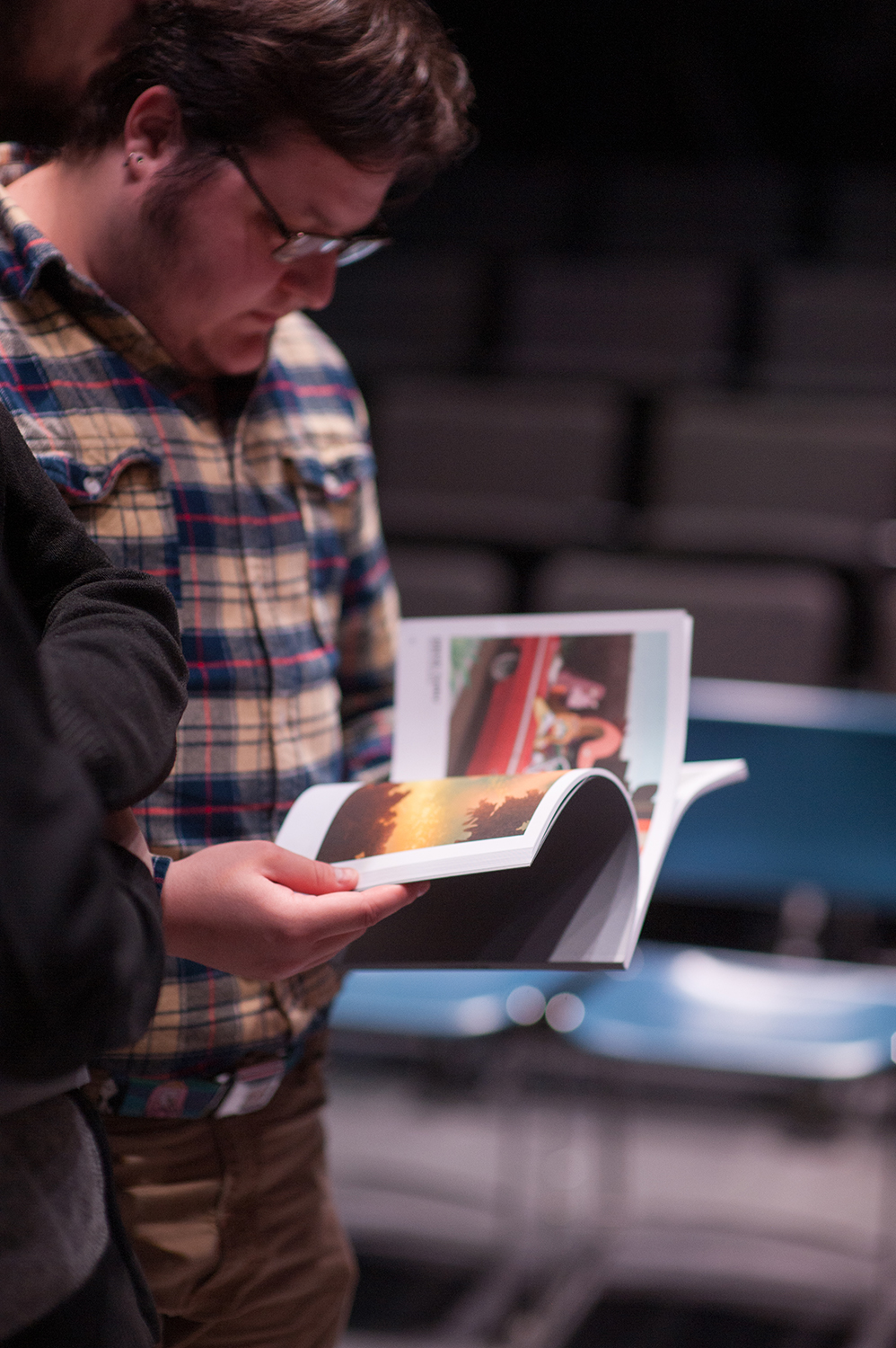 Man in flannel shirt flipping through Bravura.