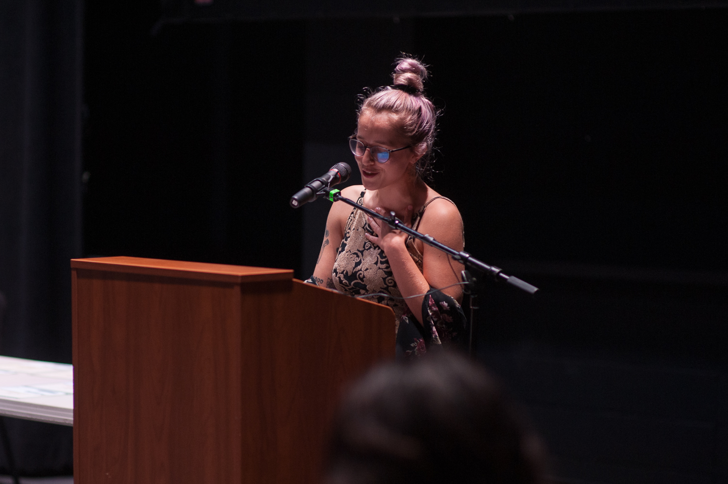 Young woman reading her poem at a podium.