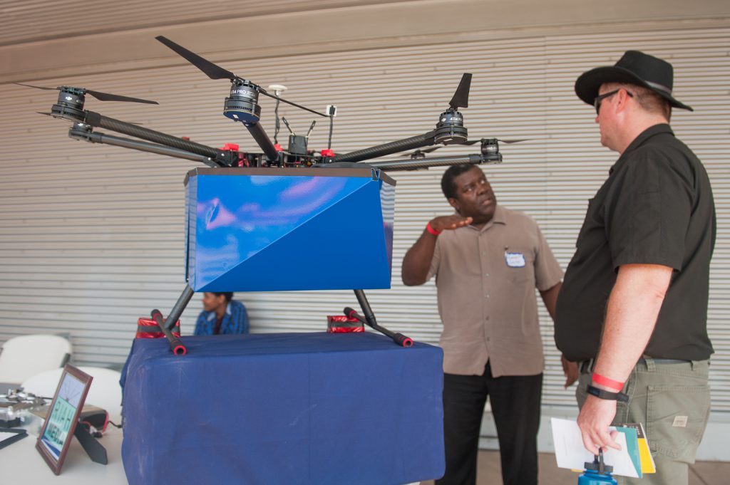 Drone inventor and exhibitor engaged in conversation at a booth