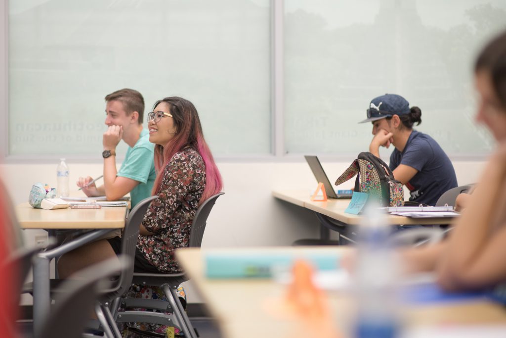 Three students at desks in classroom