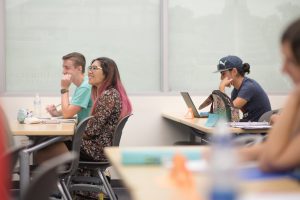 Three students at desks in classroom