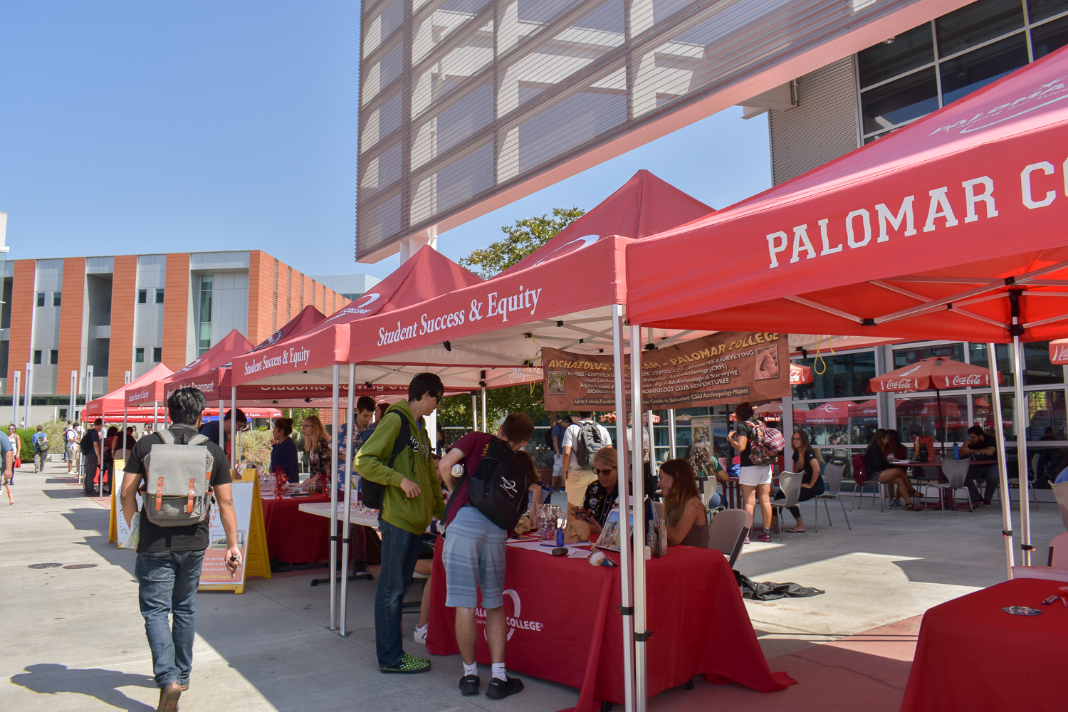 Students walking on campus with red Palomar information canopies and tables set up