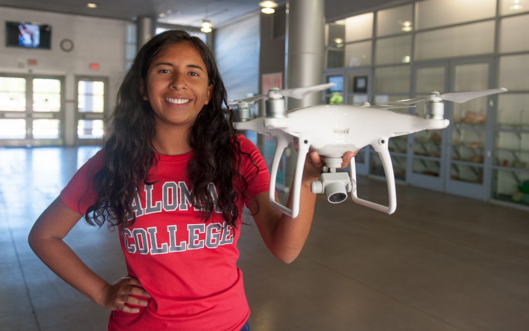 Drone student wearing a red Palomar College shirt and holding drone