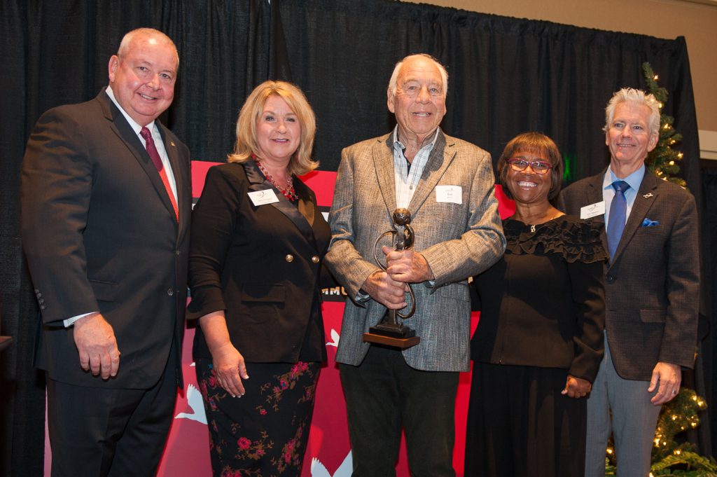 Palomar leadership, staff and guests standing with the 2018 Comet Award recipient holding his award