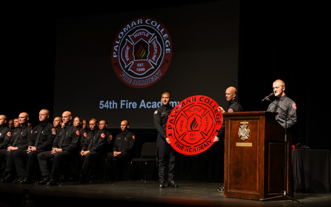 Speaker at podium and cadets on stage at the Fire academy graduation ceremony