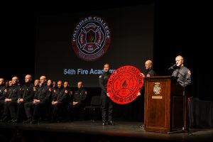 Speaker at podium and cadets on stage at the Fire academy graduation ceremony