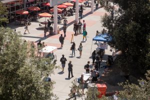 Busy campus with students walking and talking and wearing backpacks