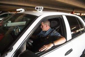 Palomar College Police Department officer in uniform checking parking permits inside cruiser