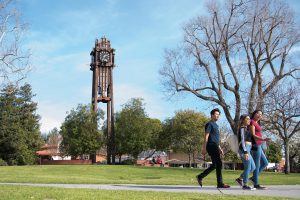 Three students walking on campus in front of the clocktower