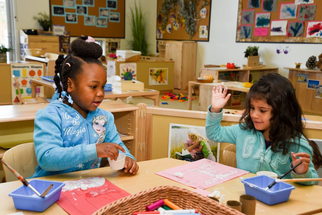 Two children doing an art craft at a table