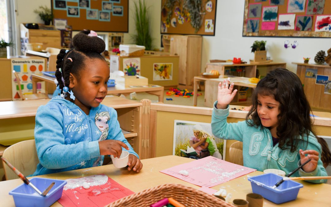 Two children doing an art craft at a table