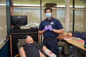 EMT student in classroom with a training dummy