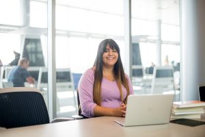 Student sitting at a table in front of a laptop