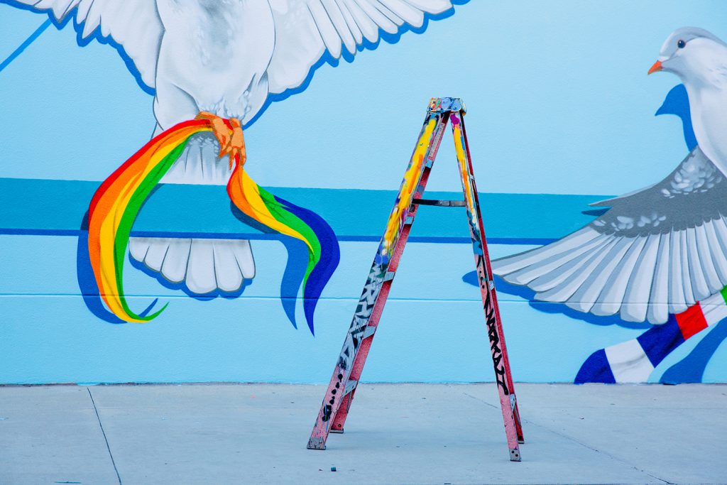 Mural on a wall of birds holding ribbons