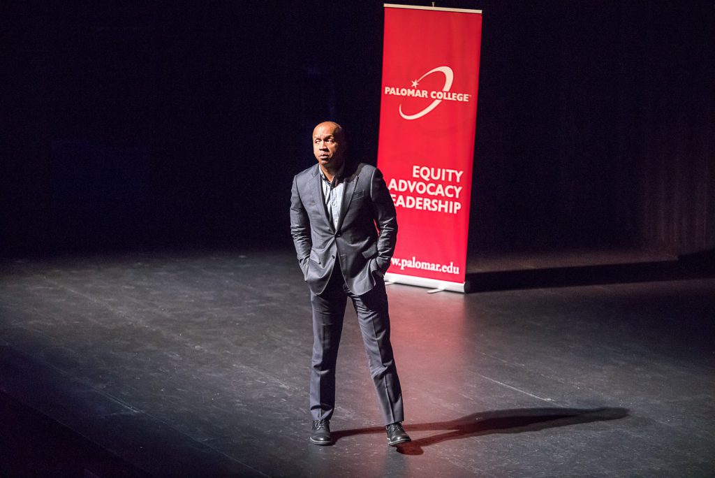 Speaker on stage with a banner for Equity Advocacy Leadership