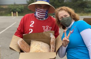 Two staff members holding a box of food in preparation for the Palomar food distribution event