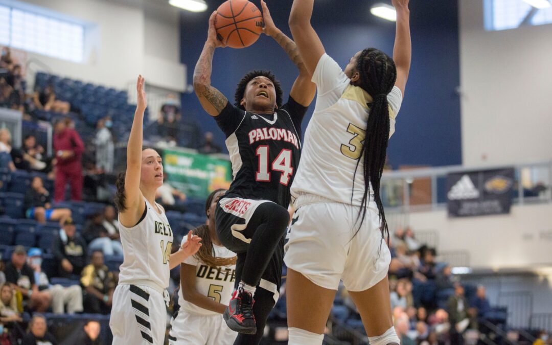 Women's basketball player going up for a shot against a defender