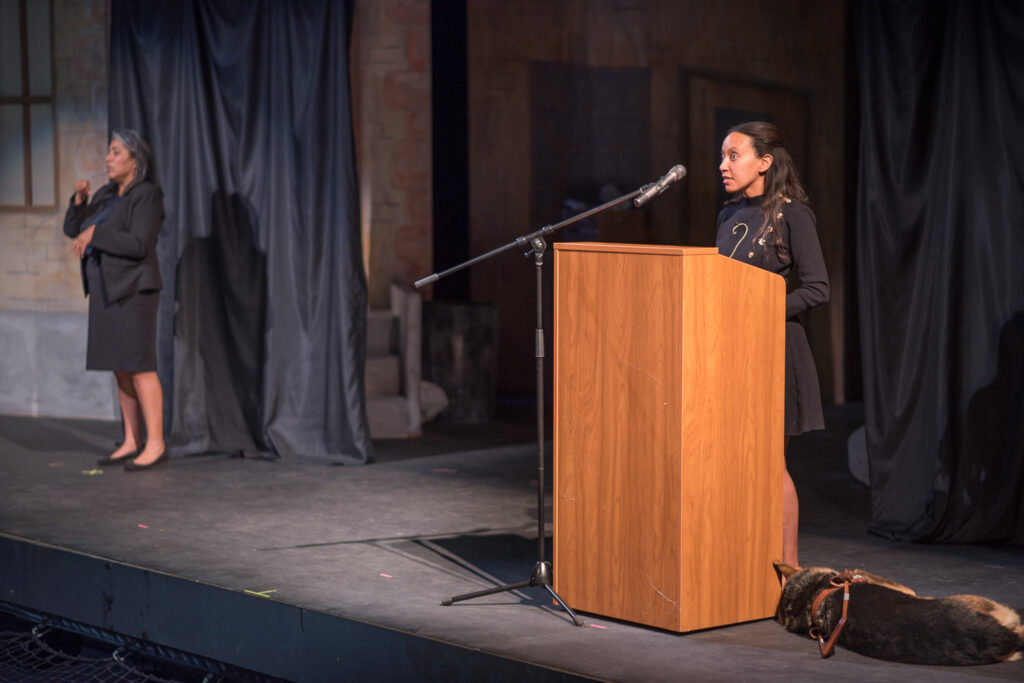 Haben Girma stands at a podium on stage at Palomar College's Brubeck Theatre, while her sign language interpreter stands to the left