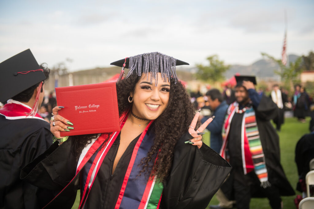 Palomar College Graduate Student holding up her diploma