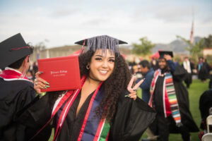 Palomar College Graduate Student holding up her diploma