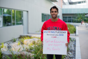 Palomar College Student holding a sign that says Giving Tuesday. Because you can give I can get an education ands support my family