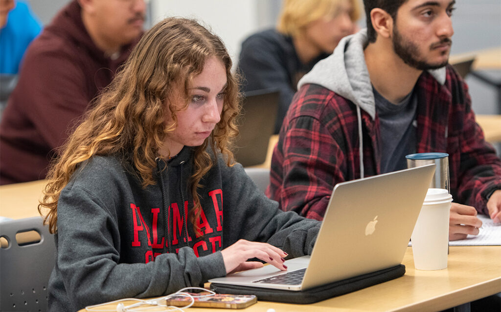 Palomar College student wearing a Palomar College sweatshirt looking into her laptop.