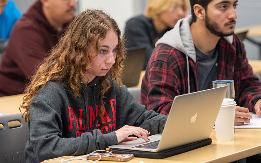 Palomar College student wearing a Palomar College sweatshirt looking into her laptop.