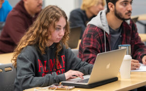 Palomar College student wearing a Palomar College sweatshirt looking into her laptop.
