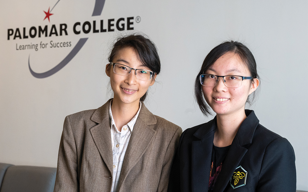 Baccalaureate students Irena and Faith Sun standing in front of the Palomar College logo at the Rancho Bernardo Education Center