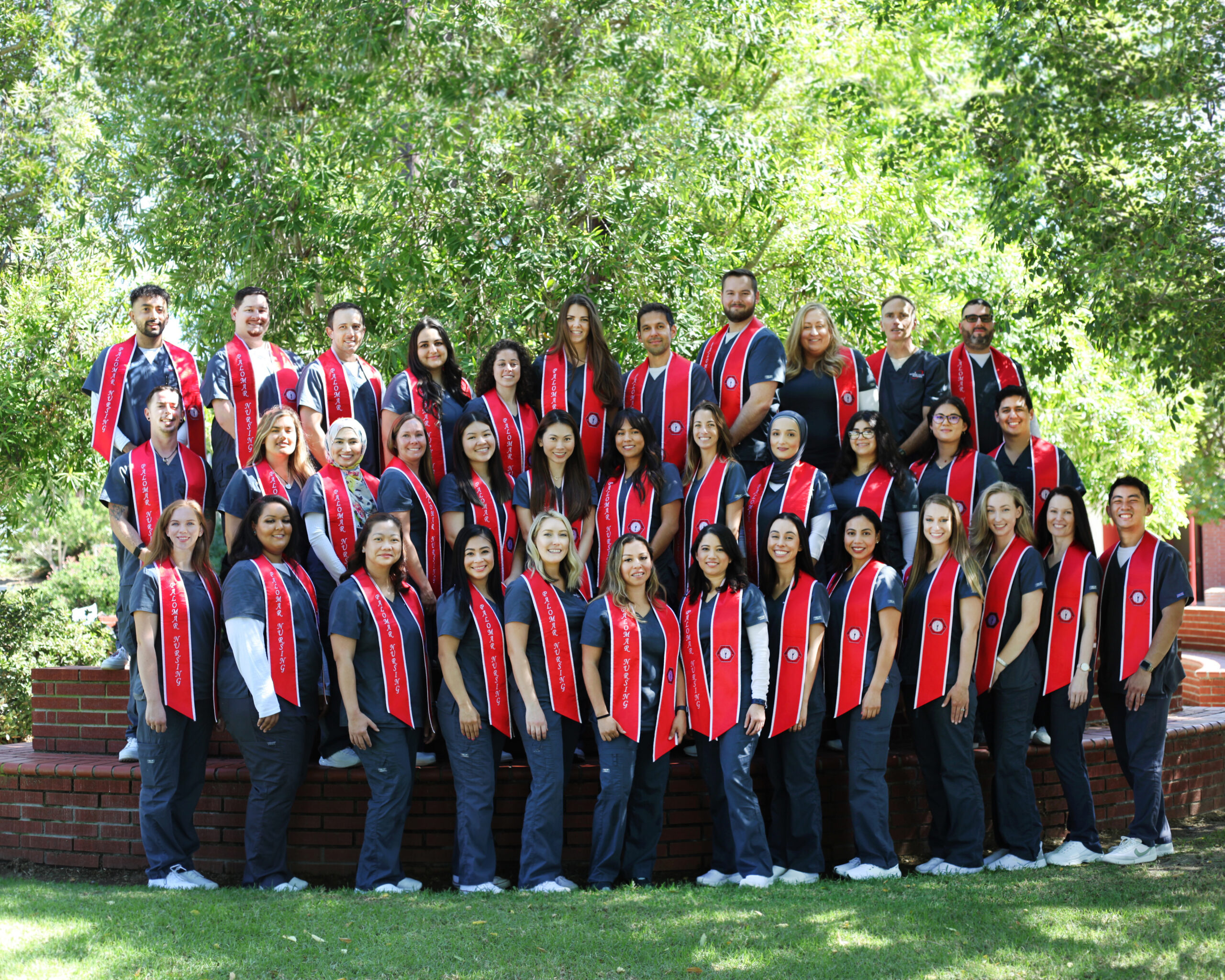 group photo of nursing students wearing scrubs and graduation stoles